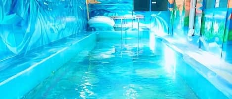 A pool area with clear water, a bench, and a wall with a mural.