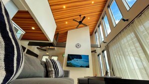 A modern interior with a wooden ceiling, a clock, a large window, and a sofa. - Kyoran Fukatei (Tateyama)