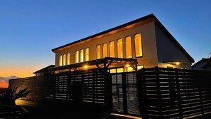 A modern two-story house with a sloped roof and large windows, surrounded by a wooden fence. - Kyoran Fukatei (Tateyama)