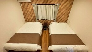 A room with two beds, wooden flooring, a wooden ceiling, and a curtain. - Kyoran Fukatei (Tateyama)