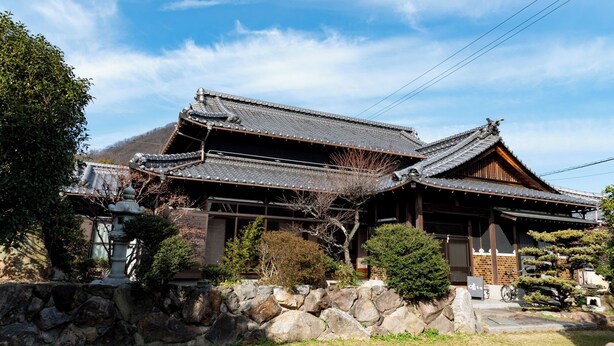 A traditional Japanese building with a tiled roof, wooden structure, and stone wall. - Totsutotsutotsu (Mitoyo)
