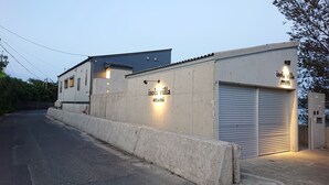 Um edifício com uma placa que diz 'Isola Villa Amami' e uma porta de garagem fechada.