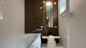 A modern bathroom with a bathtub, a mirror, and a shower head. - Tabino Hotel Villa Miyakojima (Miyakojima)