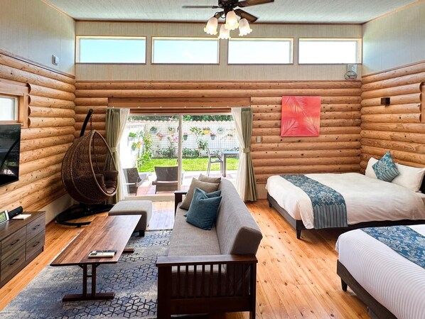 Habitación de cabaña de madera con cama, sofá y una silla colgante. Hay una ventana y vistas al exterior.
