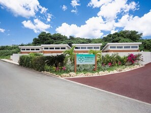 A modern building with a sign in front, surrounded by greenery and a clear sky. - Tabino Hotel Villa Miyakojima (Miyakojima)