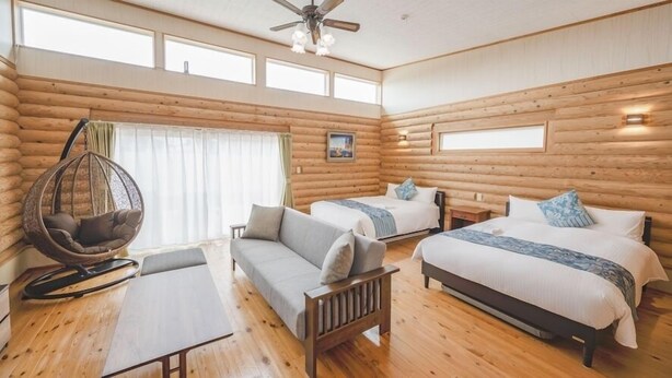 A log cabin room with two beds, a hanging chair, a sofa, and a table. - Tabino Hotel Villa Miyakojima (Miyakojima)
