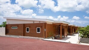 A row of log cabin-style buildings with a flat roof and a covered walkway. - Tabino Hotel Villa Miyakojima (Miyakojima)