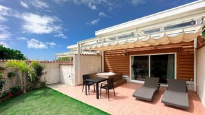 A patio with a table and chairs, a hot tub, and lounge chairs. - Tabino Hotel Villa Miyakojima (Miyakojima)