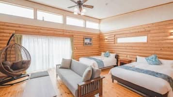 A log cabin room with a bed, two sofas, a hanging chair, and a ceiling fan.