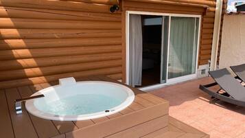 A wooden cabin with a hot tub and a patio area.