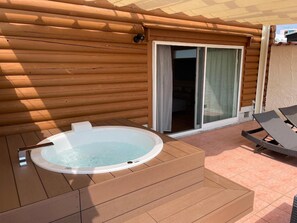 Una cabaña de madera con jacuzzi y zona de patio.