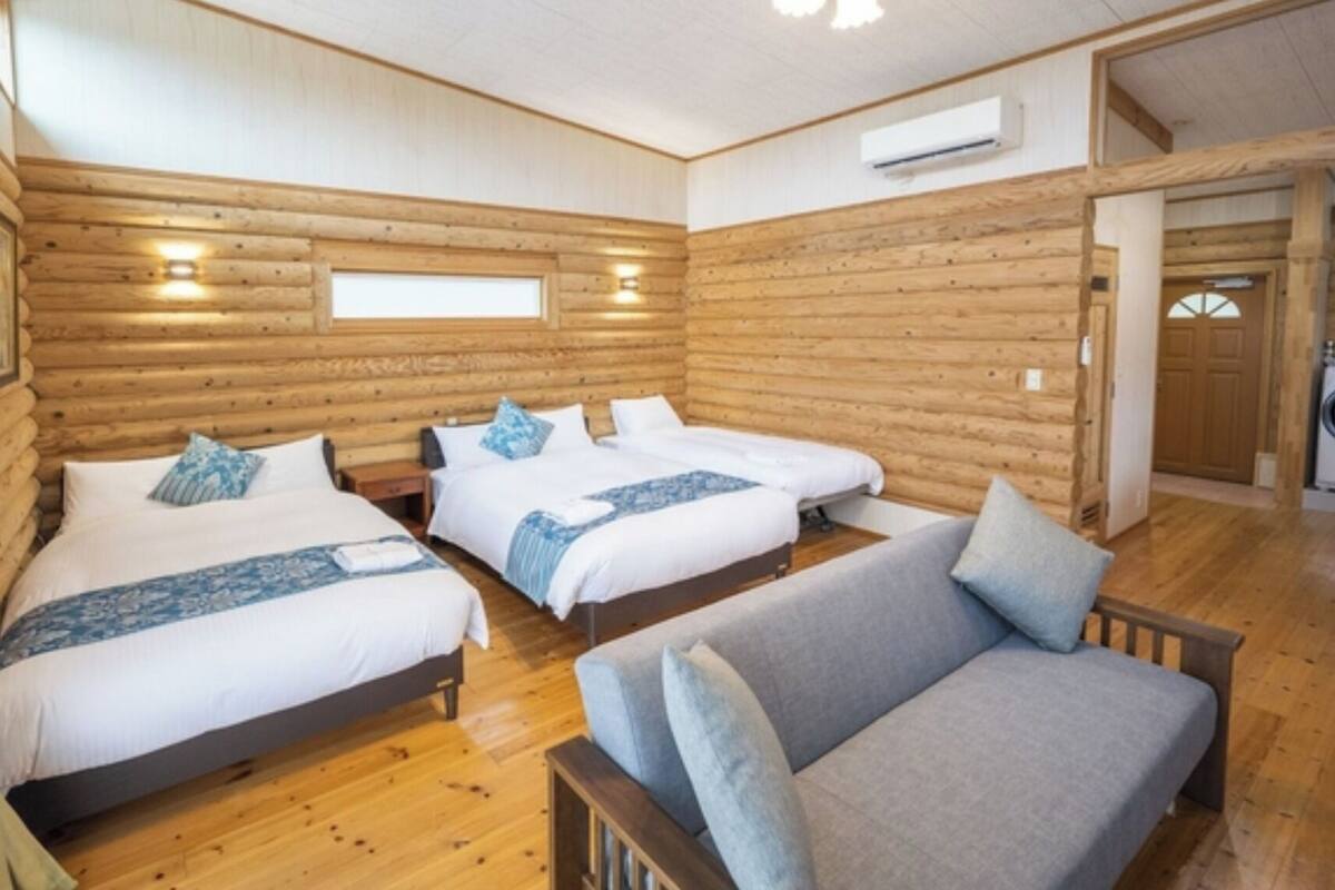 Una habitación tipo cabaña de madera con tres camas, un sofá y una lavadora.