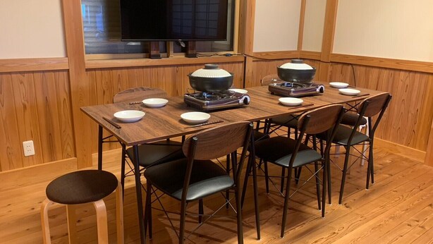 A dining area with a wooden table, four chairs, a television, and a grill. - ARS Hotel Nikko/imaichi (Nikko)