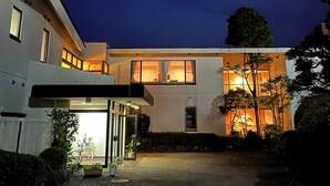 Ein modernes, zweistöckiges Haus mit gut beleuchtetem Eingang und einem sichtbaren Mond am Nachthimmel.
