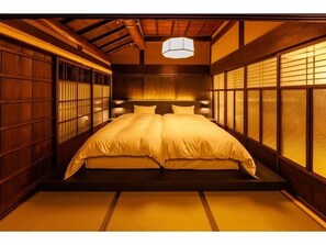 Une pièce de style japonais traditionnel, avec un sol recouvert de tatamis, un grand lit à baldaquin et des portes coulissantes en papier de riz (shoji).