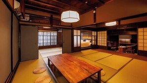 Une pièce de style japonais traditionnel, avec un sol recouvert de tatamis, une table en bois et un lit équipé d’un futon.