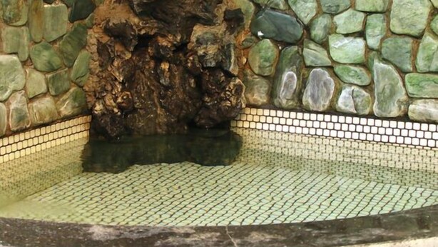 A stone wall with a mosaic border and a central rock formation. - Annex Kawanatsu (Shinonsen)