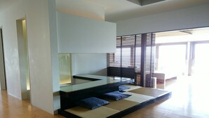 Ein modernes Interieur mit Glastisch, gepolsterten Sitzmöglichkeiten und Blick durch eine Holzabtrennung.