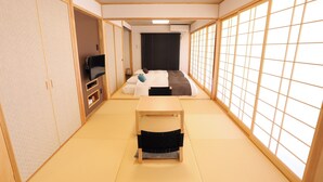A traditional Japanese room with tatami flooring, a futon bed, a small wooden table, and sliding doors. - Tabinoteitaku Okinawa Nakijin Homann Concept (Nakijin)