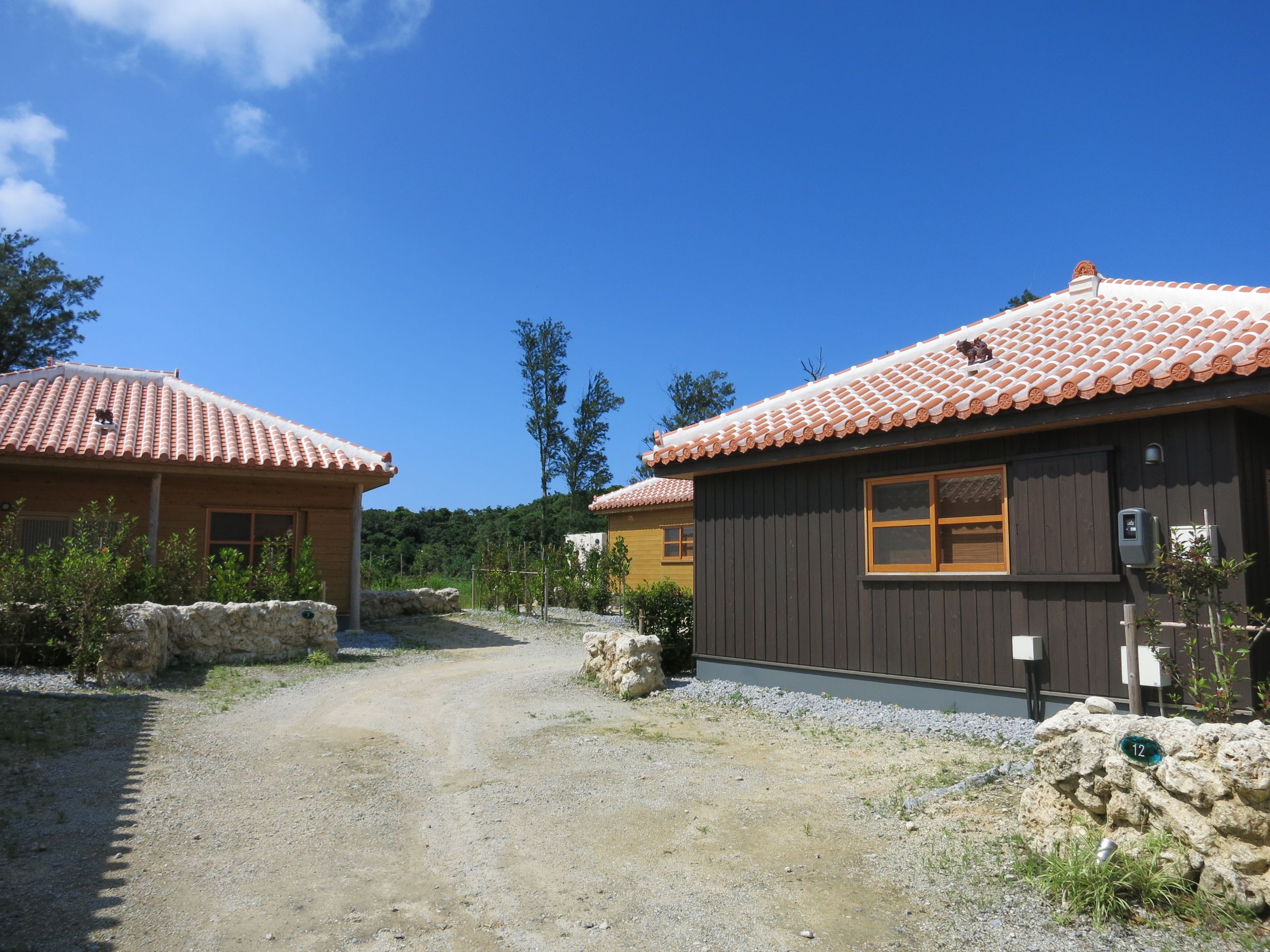 A rural setting with traditional buildings, a gravel path, and a clear blue sky.