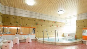A large indoor swimming pool with a tiled floor, a hot tub, and a changing area with benches. - Hotel Shugetsukan (Akita)
