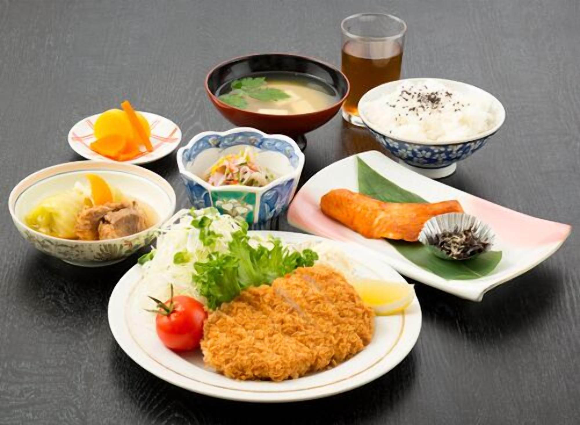 A variety of Japanese dishes including a bowl of soup, a plate with a fish fillet, and a bowl of rice with seaweed.