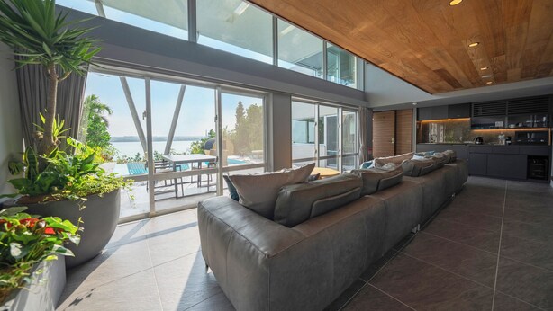 Una sala de estar moderna con un sofá grande, un comedor y vistas a una piscina y montañas.