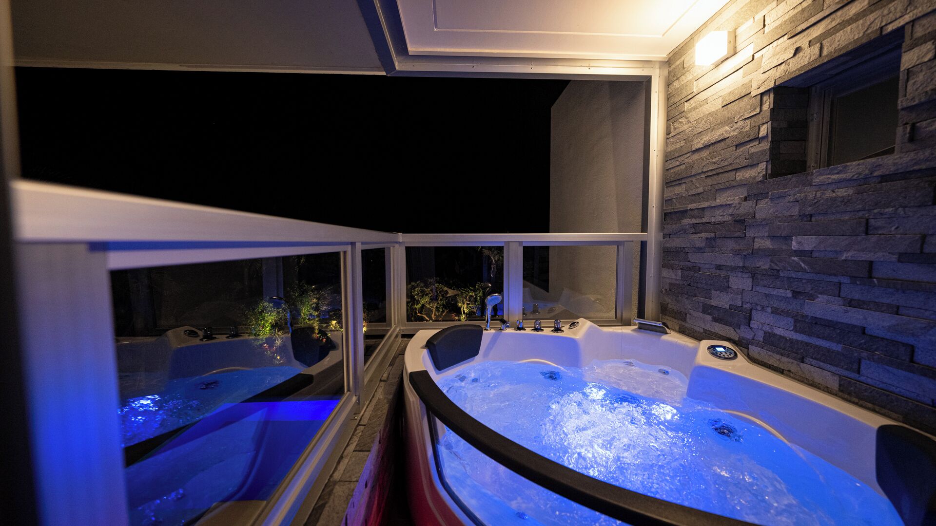 Un área de jacuzzi con pared de piedra y amplias ventanas.