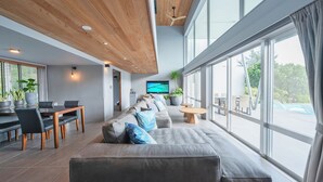 Un espacio moderno para la vida con sofá, mesa de comedor, sillas, ventanas amplias y televisión.