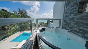 Un jacuzzi con terraza acristalada, piscina y pared de piedra.