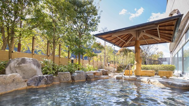 A traditional Japanese onsen with a wooden structure, stone steps, and a bamboo fence. - Stella Glamping Guesthouse (Nakatsugawa)
