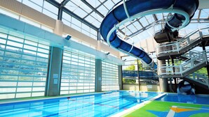 An indoor water park with a large slide, a pool, and a glass-enclosed area with windows. - Stella Glamping Guesthouse (Nakatsugawa)