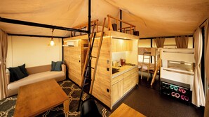 A compact, well-lit tent-style room with bunk beds, a wooden desk, a sofa, and a small kitchenette. - Stella Glamping Guesthouse (Nakatsugawa)