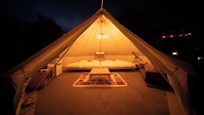 A tent with a central sleeping area, a small table, and a lamp. - Stella Glamping Guesthouse (Nakatsugawa)
