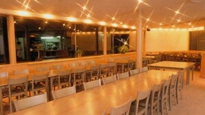 A spacious dining area with multiple tables and chairs, large windows, and a bright interior. - Hotel Cho (Yuzawa)