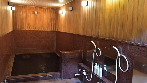 Un cuarto con paneles de madera, una bañera grande, una zona de ducha y un espejo con artículos de tocador.