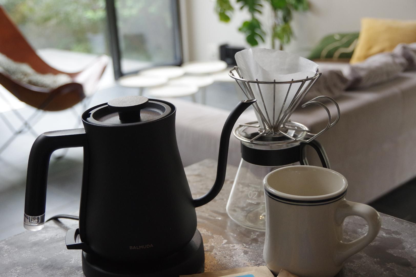 A kitchen with a coffee maker, a mug, and a glass container on a table.