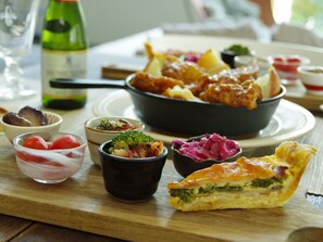 A wooden table with a variety of dishes including a quiche, a bowl of red cabbage, and a glass of white wine. - The Canvas Hayama Park (Hayama)
