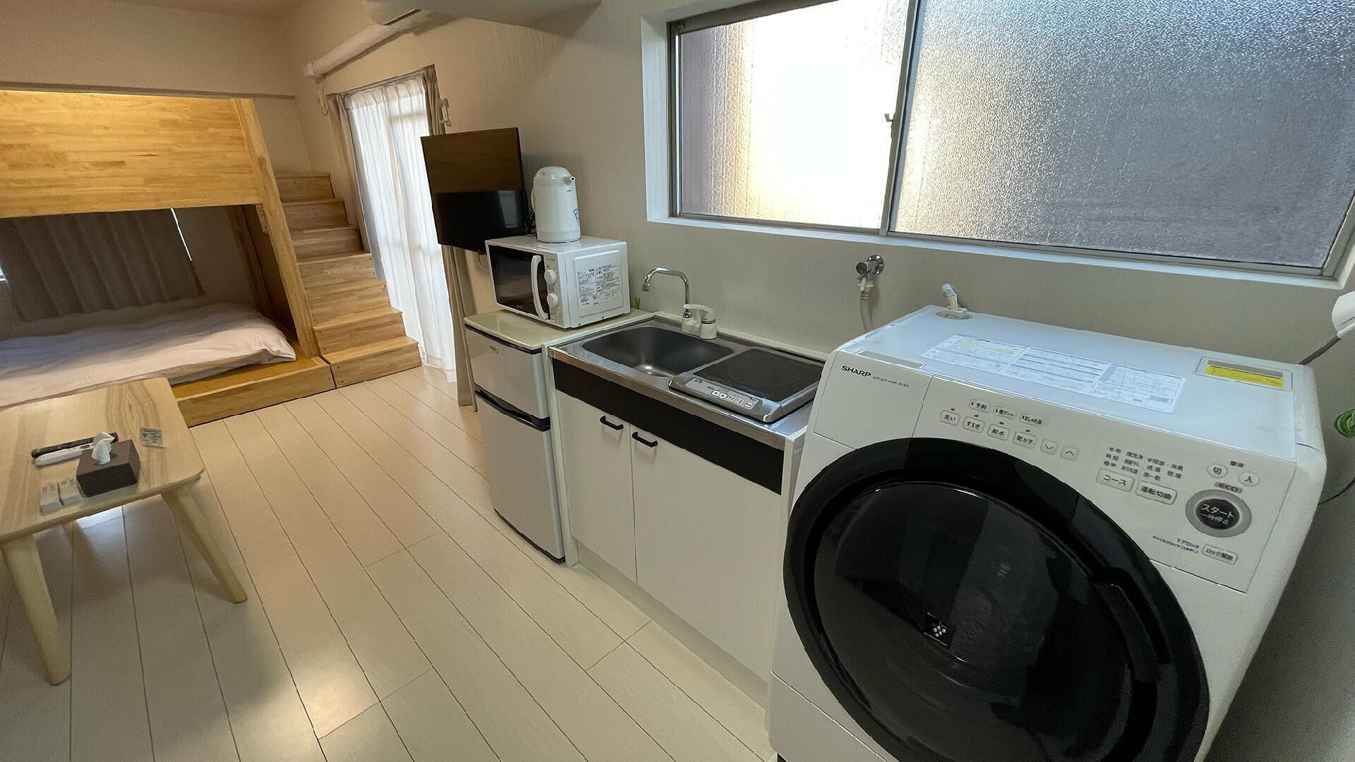 A compact kitchen with a washing machine, a microwave, and a sink.