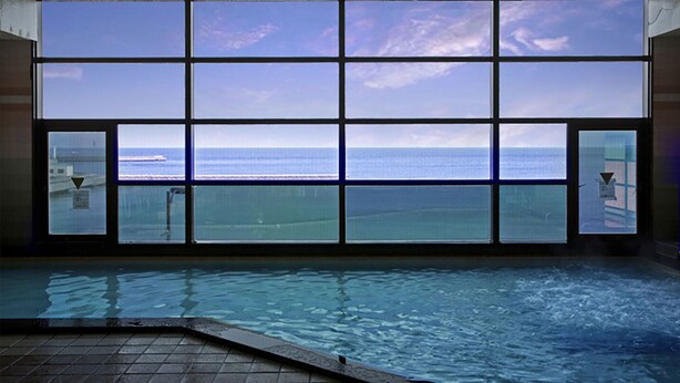 Area piscina con vista sull'oceano attraverso ampie finestre.