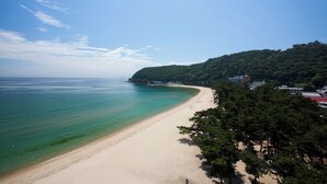 Una spiaggia con acque turchesi cristalline, una costa sabbiosa e un promontorio boscoso sullo sfondo.