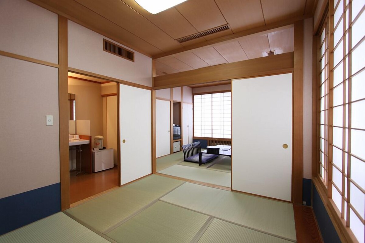 A traditional Japanese room with tatami flooring, sliding doors, and a low table with cushions.