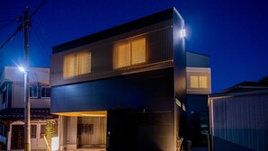 Un edificio moderno de dos pisos con fachada oscura y ventanas iluminadas.