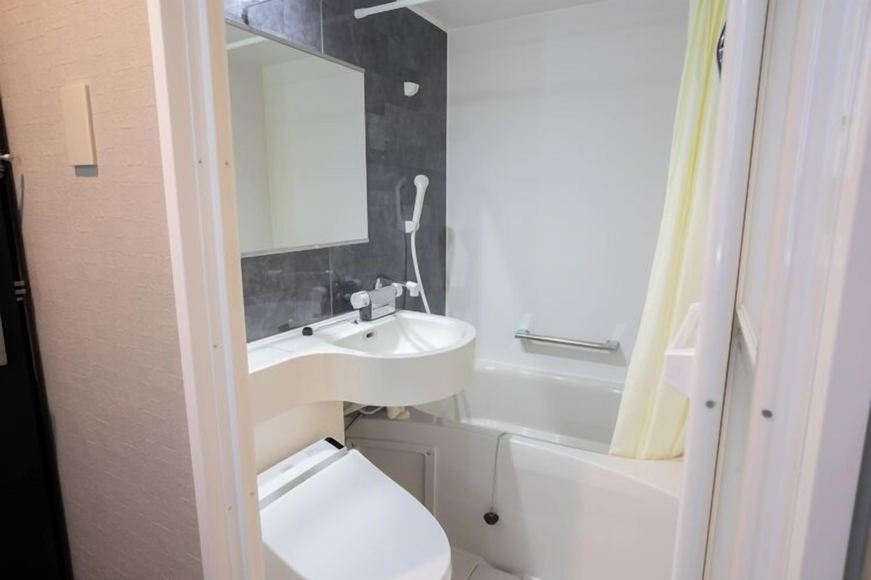A bathroom with a white sink, mirror, and bathtub.