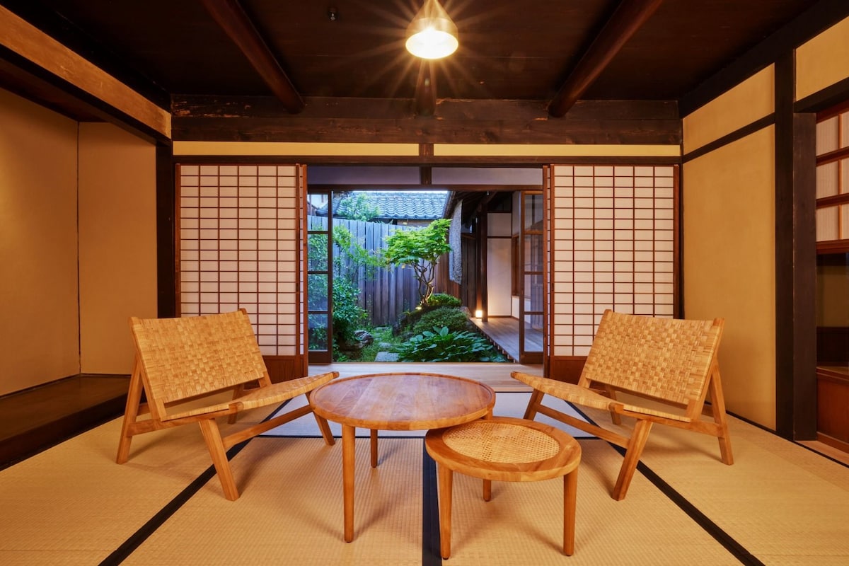 Una habitación tradicional japonesa con suelo de tatami, una mesa de madera baja y dos sillas tejidas.