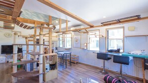A room with a cat tree, a wooden ceiling, a window, and a bar area. - Hotel Fit In Ishigakijima (Ishigaki)