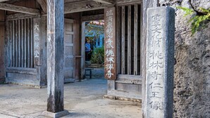 A traditional wooden building with a stone pillar inscribed with text. - Hotel Fit In Ishigakijima (Ishigaki)