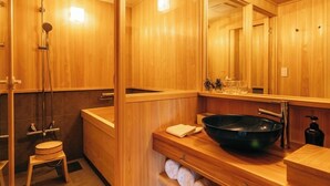 Une salle de bain en bois avec un grand miroir, un lavabo noir et un porte-serviettes.