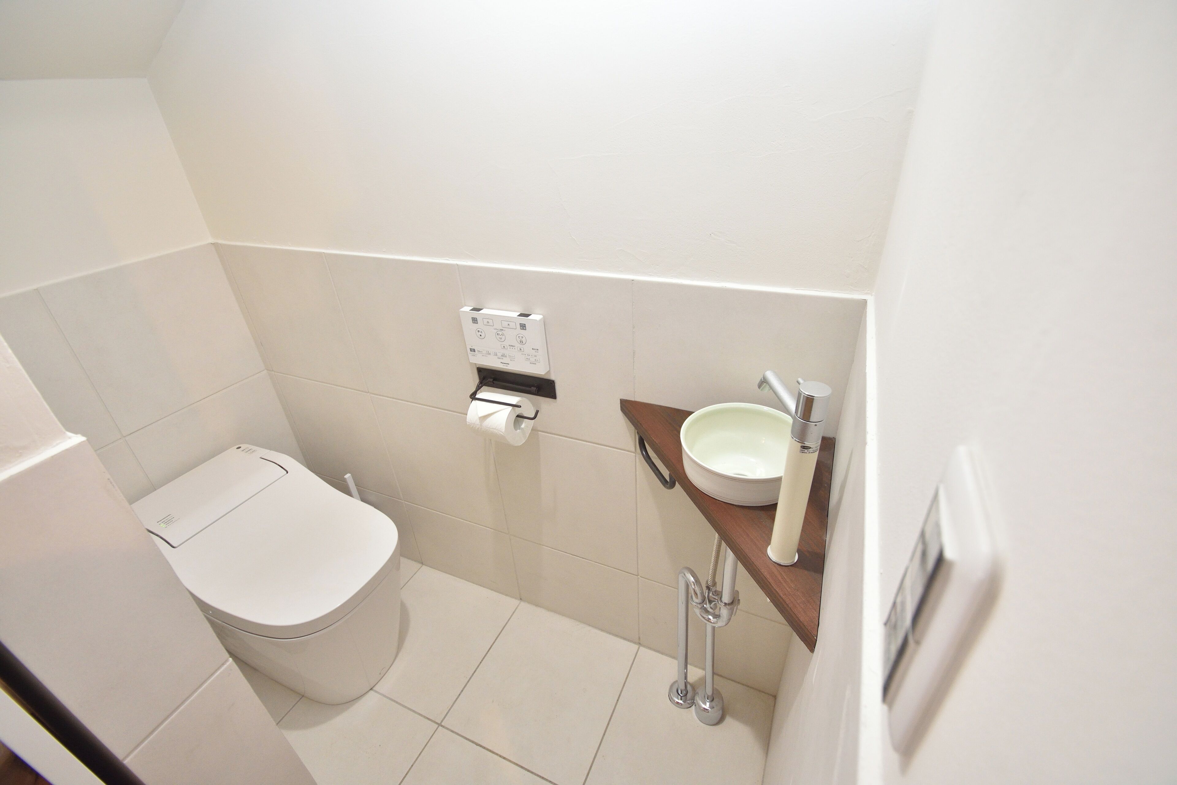 A small, clean bathroom with a toilet, a sink, and a towel dispenser.