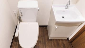 A small bathroom with a toilet, a sink, and a control panel.